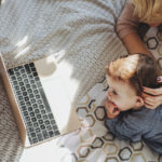 Mother and baby looking at a laptop checking reviews.